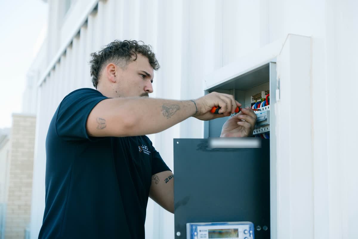 James working inside a switchboard with a screwdriver