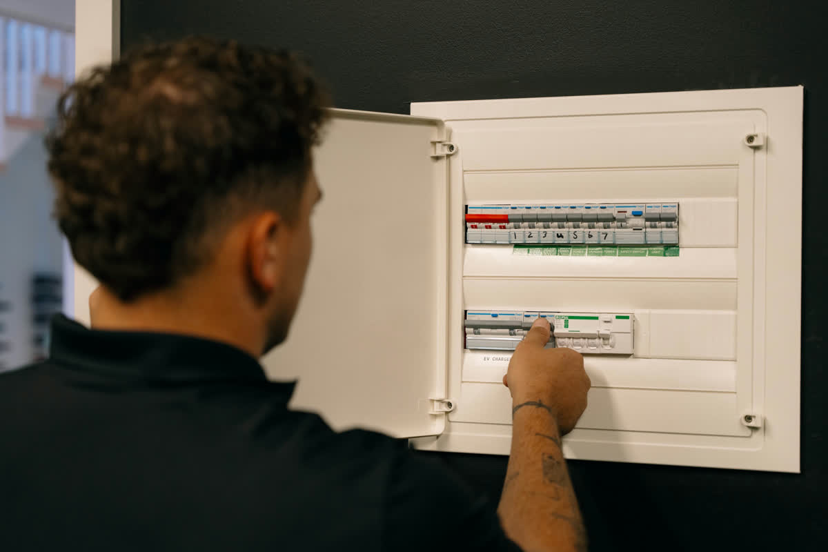 A JJC electrician checking the breakers in a modern switchboard