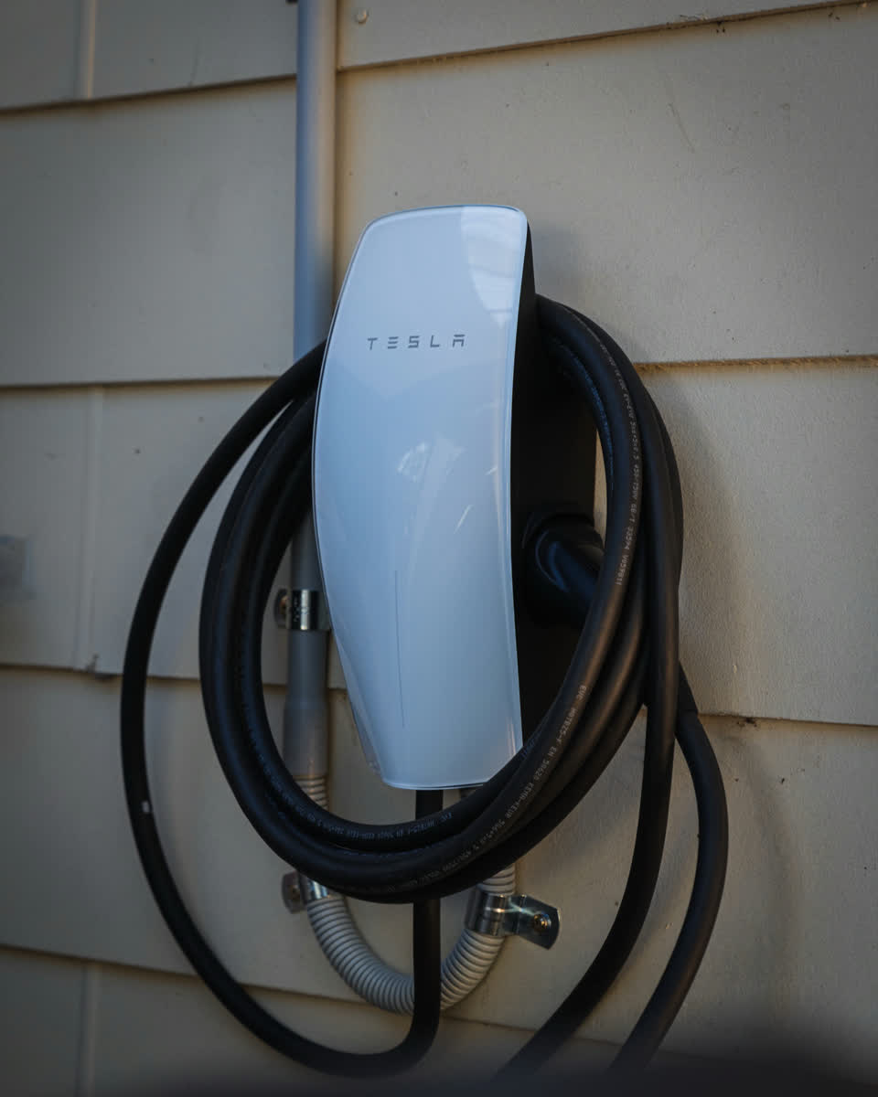 A Tesla Wall Connector installed on a weatherboard wall