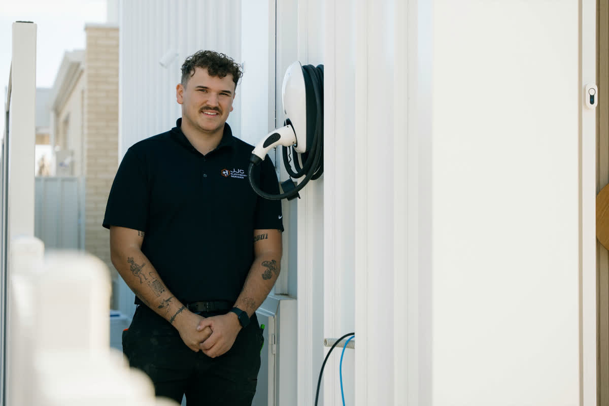 James beside a newly installed EV charger on a white wall