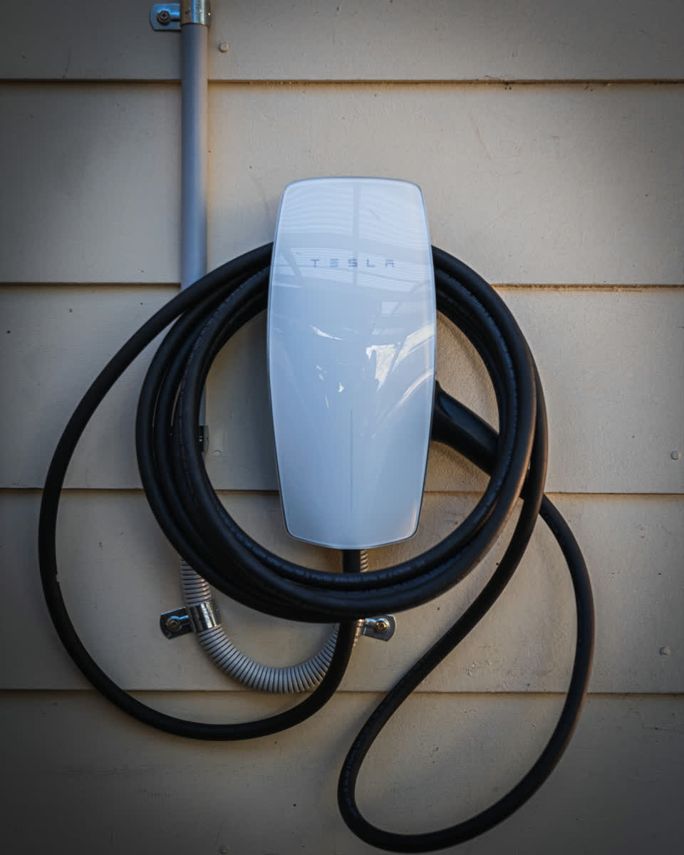 A Tesla Wall Connector installed on a weatherboard wall