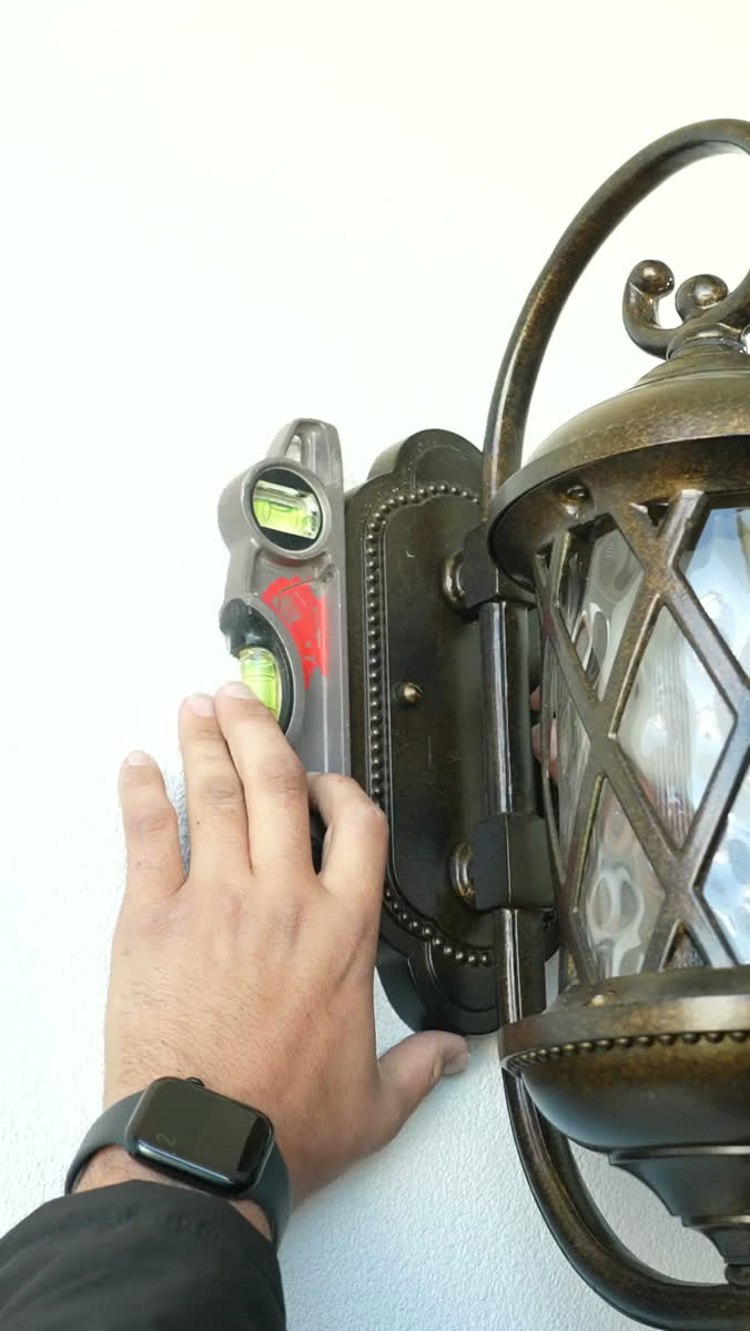An electrician fitting an outdoor wall lantern